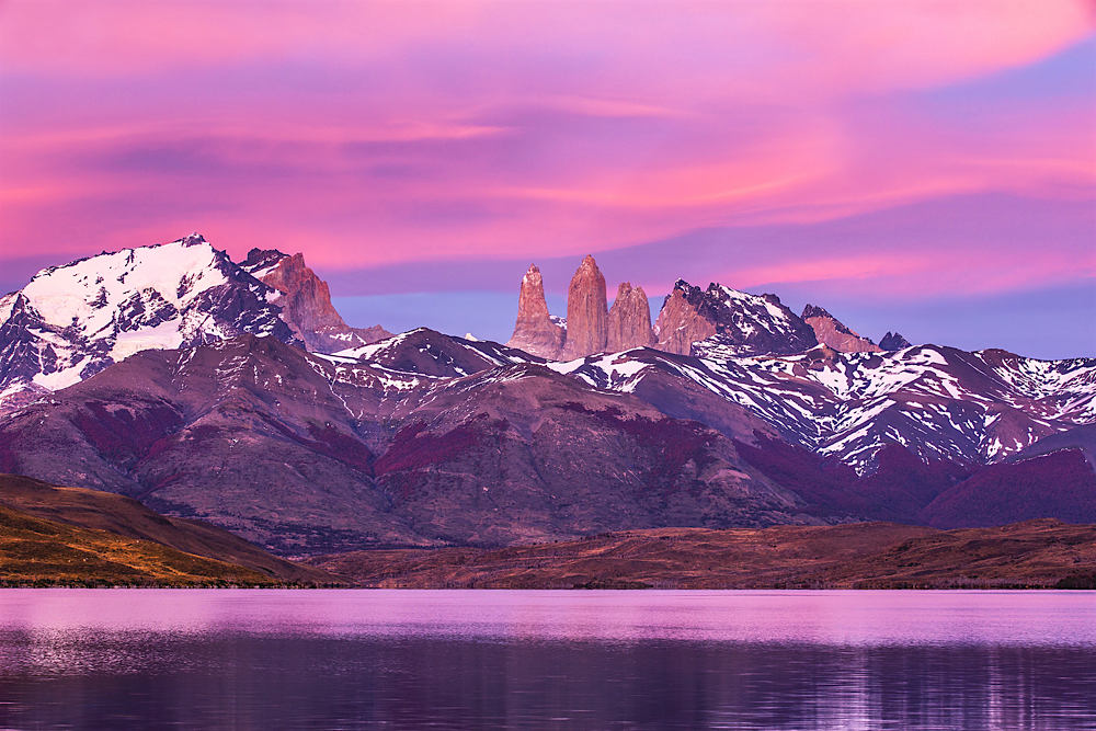 The peaks of Torres del Paine at light of dawn on a lake, reflection